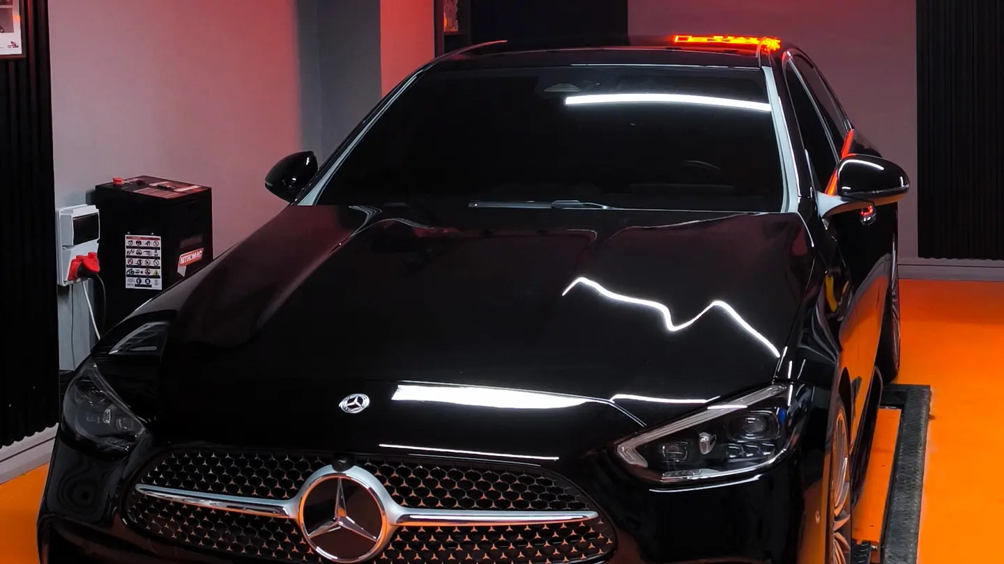 Seramik kaplama sonrası Mercedes-Benz C serisinin kaputunda stüdyo aydınlatmasının yansıması, Peak Detailing stüdyosunda ışıkta kontrol